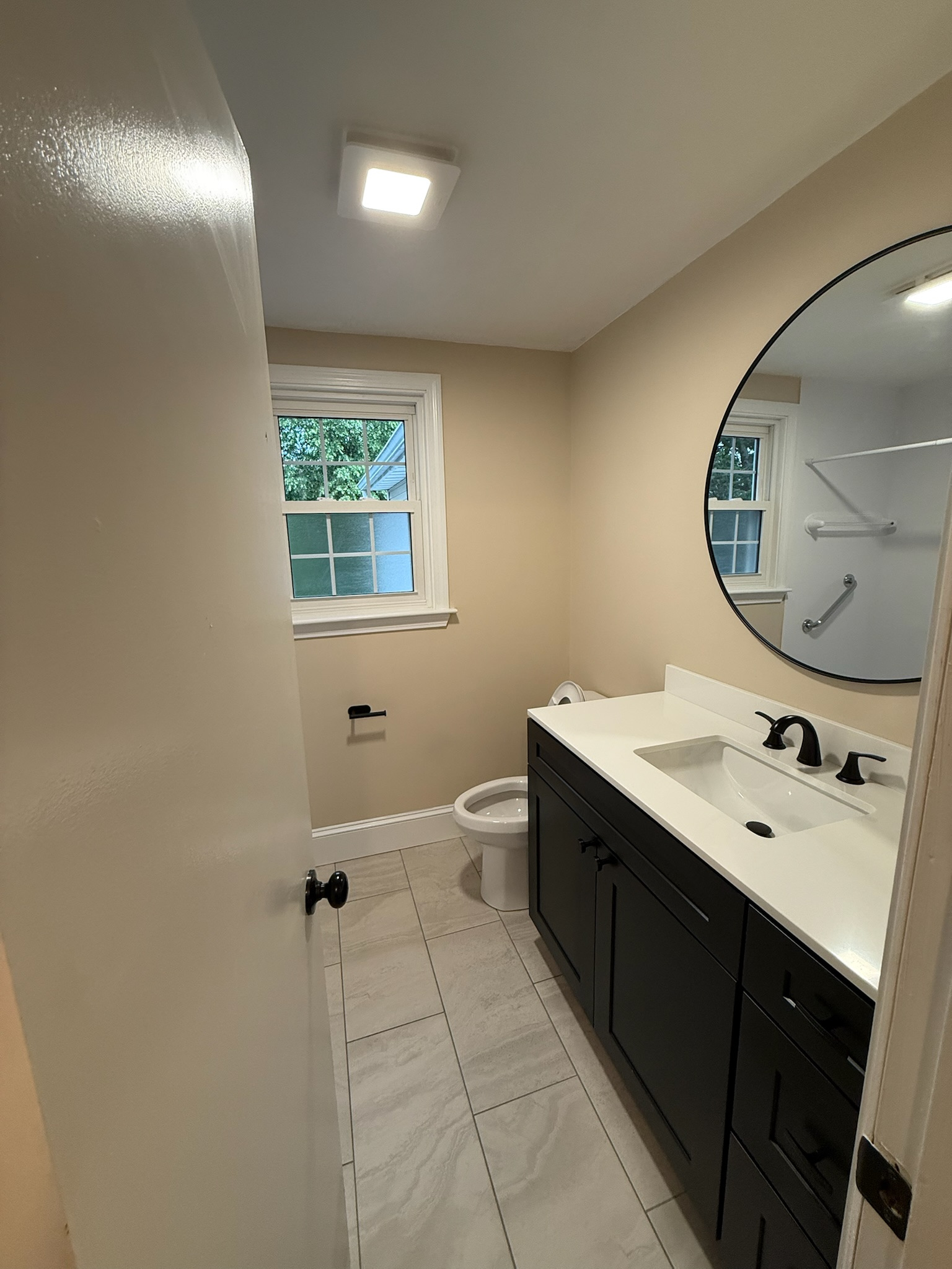 Stoneham bathroom — dark vanity with matte black hardware and round mirror