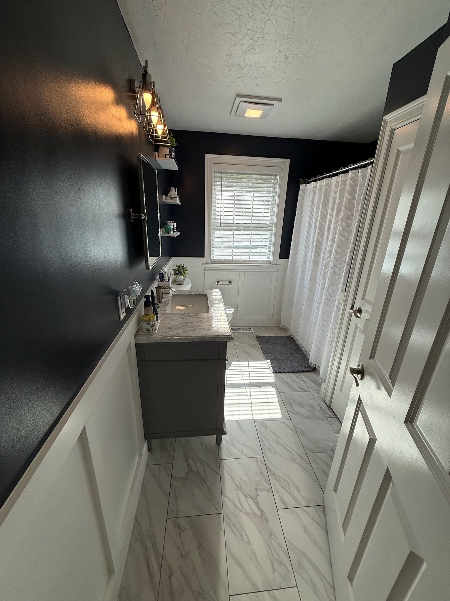Tewksbury bathroom — dark navy walls with white wainscoting and marble tile